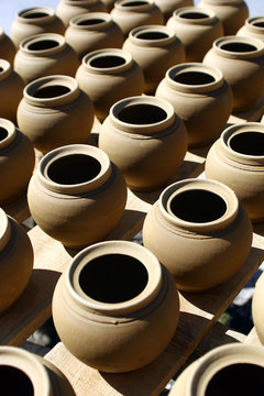 pottery set up in a row in the sun to dry