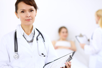 Fototapeta premium Female doctor smiling on the background with patient and his doctor