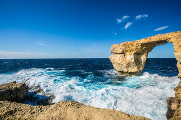 Gozo, azure window, stone arch hit by waves on a windy and sunny day