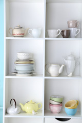 Different clean dishes on wooden shelves