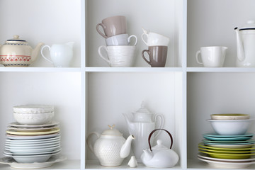 Different clean dishes on wooden shelves