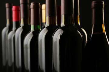 Wine bottles in a row on black  background, close up