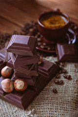 Roasted coffee beans, chocolate, nuts and cup on the wooden background