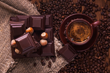 Roasted coffee beans, chocolate, nuts and cup on the wooden background