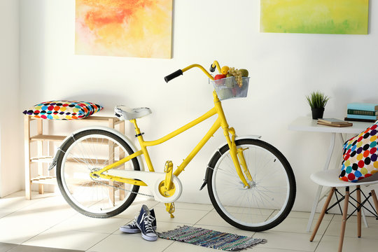 Yellow bicycle with sneakers in light living room interior