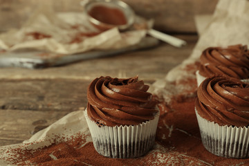 Chocolate cupcakes on baker paper over wooden background