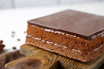 Delicious chocolate cake on wooden cutting board closeup