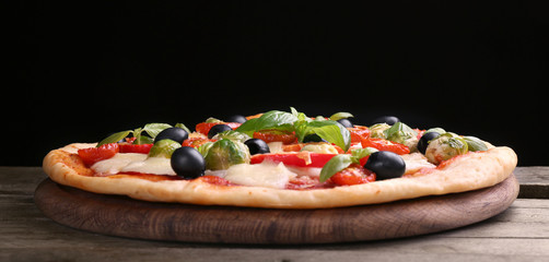 Delicious pizza with cheese and vegetables on black background