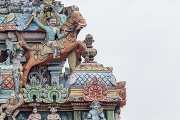 Trichy, India - October 15, 2013: Closeup of  decoration on one Gopuram at Shirangam temple. Fighting man on brown horse seems to jump off the temple. Pastel colors, gray sky.