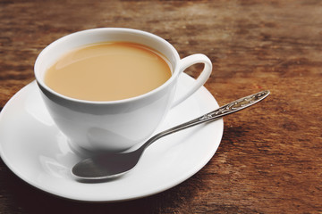 Porcelain cup of tea with milk on wooden background