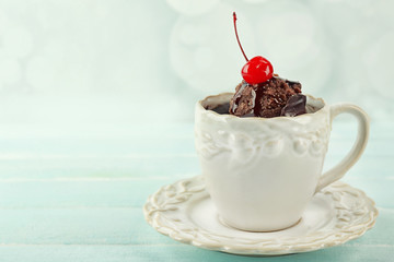 Chocolate mug cake with cream and cherry on a table