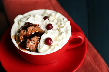 Chocolate mug cake with cream and cranberry on dark wooden background