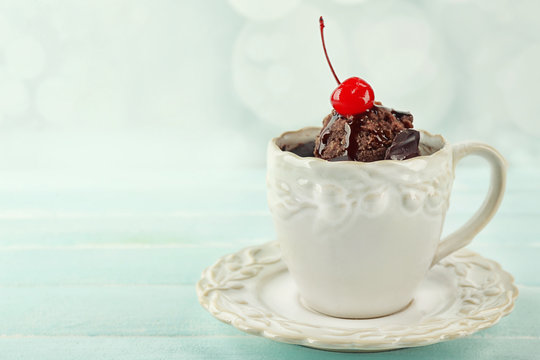 Chocolate mug cake with cream and cherry on a table