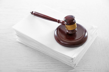 Gavel with stack of paper on wooden table closeup