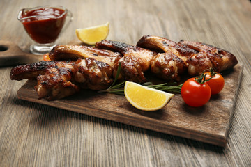 Baked chicken wings with tomatoes and rosemary on cutting board