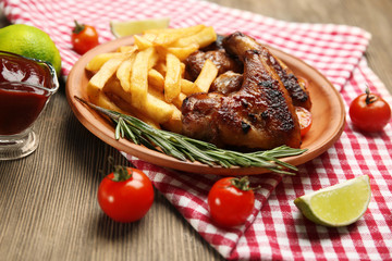Baked chicken wings with French fries on brown plate