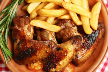 Baked chicken wings with French fries, close up