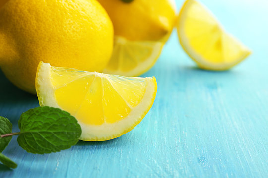 Fresh lemons with green leaves on blue table closeup