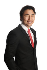 Smiling businessman looking at camera, wearing a black suit, white shirt and a red tie. Standing in front of a white background.