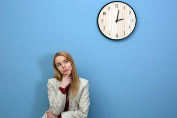 Young young beautiful woman and clock on blue wall