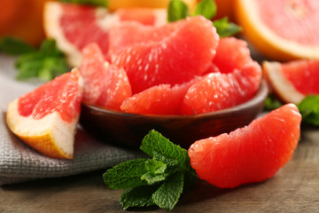 Juicy grapefruit pieces with fresh mint in a bowl, close up