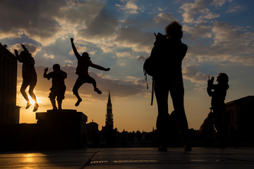 Brussels - Silhouette of jumped boys over the town on Monts des Arts in evening.