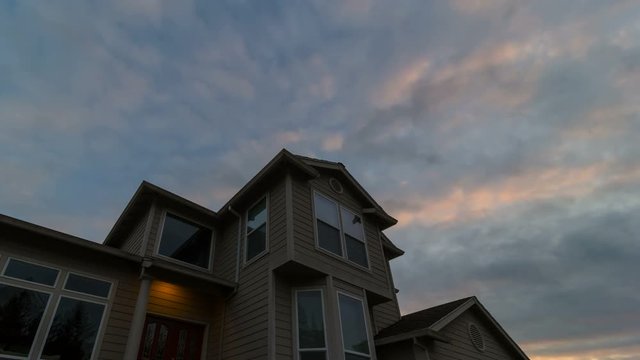 Time lapse of clouds and sunset colors with window glass reflection over the roof of house 4k