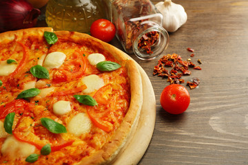 Margherita pizza with tomatoes and spices on wooden background