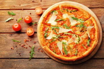 Margherita pizza with tomatoes, Parmesan and arugula on wooden background
