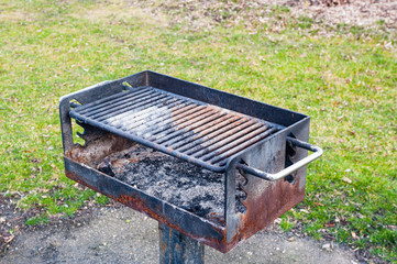 Dirty rusted barbecue grill near grass.