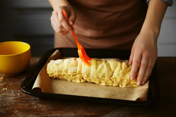 Woman spreading raw apple roll in baking tray