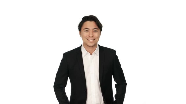 Adult businessman wearing a black suit and white shirt, standing against a white background with a big smile on his face. Video shot in 4K.
