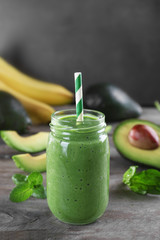 Fresh avocado smoothie with slices on wooden background © Africa Studio