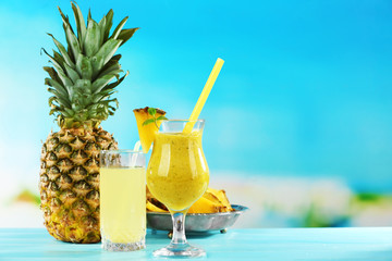 Pineapple juice and smoothie in cocktail glasses on blue background