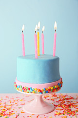 Birthday cake with candles on turquoise  background.
