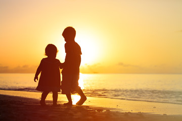 Fototapeta na wymiar little boy and girl holding hands walking at sunset