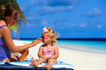 mother applying sunblock cream on daughter shoulder