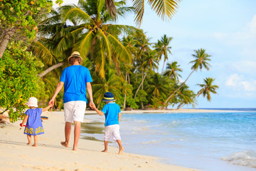 father and two kids walking on tropical beach