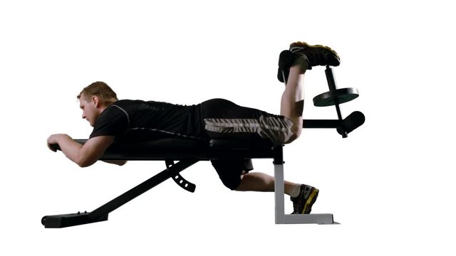 Man working out, doing leg curls on exercise bench.  Wide shot in ProRes 422HQ with clean white background, originally recorded in 12-bit 4K RAW at 24fps against green screen.