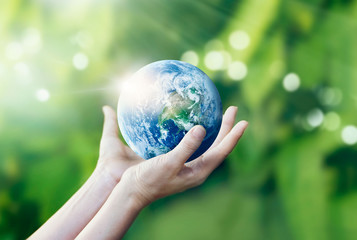 Hands holding and protecting earth on nature background