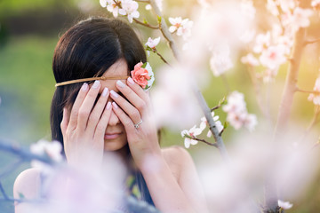 Young woman cover eyes blossom tree