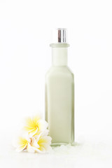 Obraz na płótnie Canvas Green cosmetic bottle with frangipani flowers