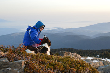 Young woman playing with dog at sunrise high in the mountain, Rila Mountains, Bulgaria