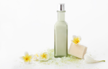 Fototapeta na wymiar Green cosmetic bottle with bath salt and frangipani flowers