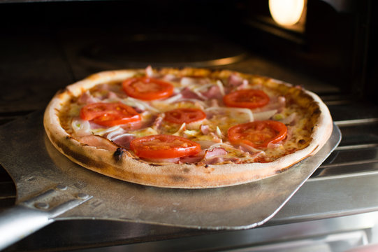 Ready-made pizza being removed from the oven.