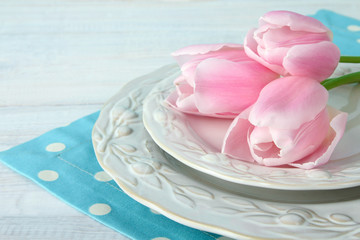 Obraz na płótnie Canvas the white and pink tulips on the plate on fabric on wooden background