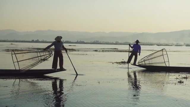 Myanmar travel attraction landmark - Traditional Burmese fishermen with fishing net at Inle lake in Myanmar famous for their distinctive one legged rowing style 4k
