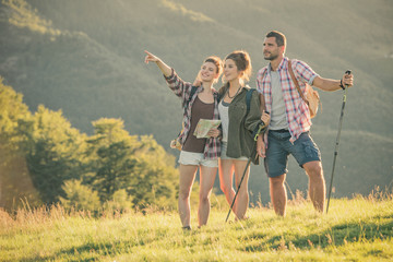 Three friends stand looking at panorama on mountain