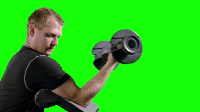 Man working out, doing bicep curls with weights on exercise bench.  Medium close up shot in ProRes 4444 with clean green background. Originally recorded in 12-bit 4K RAW at 24fps against green screen.