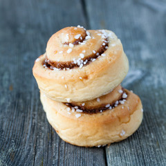 två kanelbullar på varandra mot mörk trä bakgrund
